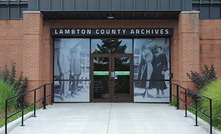 Front entrance of a brick building with black and white photos in the windows.