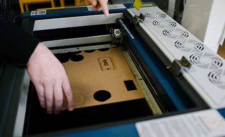 a piece of wood being laser cut using a laser cutter machine.