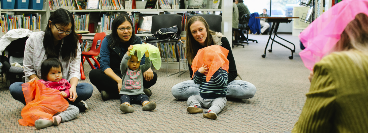 Three babies playing with their parents at the library.