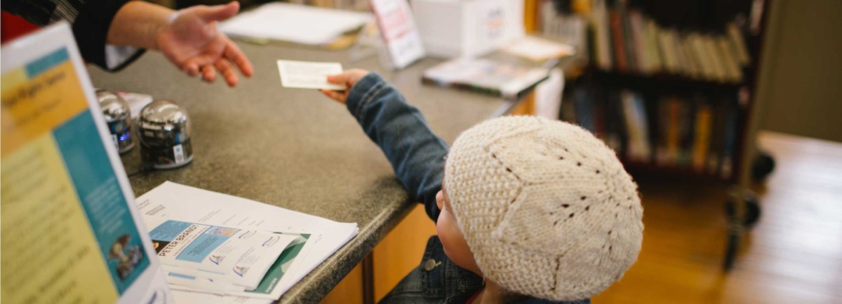 Child handing card to someone over a counter. 