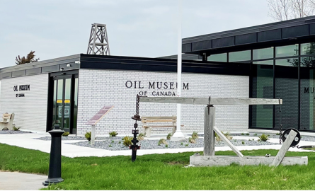 White brick building with an antique jack pump in front.