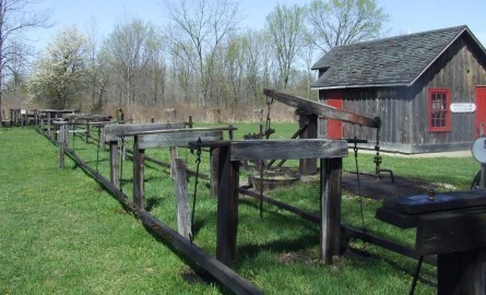 Old jack pumps outside in front of a wood building.