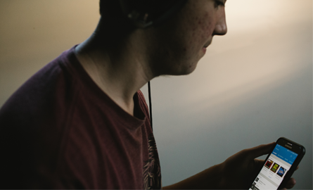 Man looking at cellphone, wearing headphones.