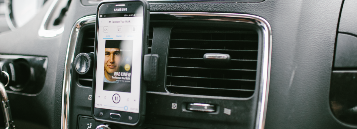 Cellphone in car with audiobook on screen. 