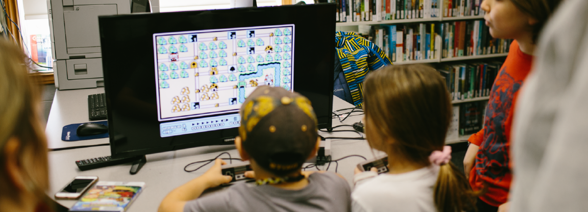 Children sitting around a table playing a video game. 