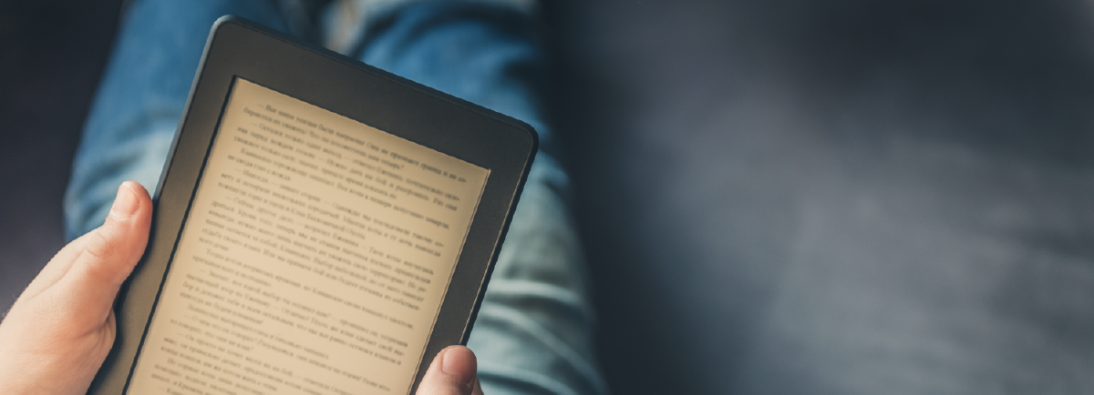 Person holding e-device reading a book. 