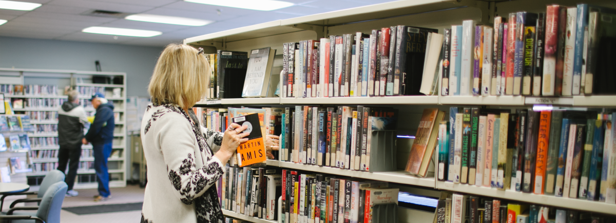 Lady pulling a book from a shelf. 