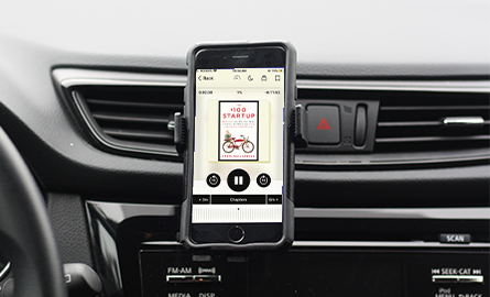 Audiobook playing on a phone on the dash of a car.