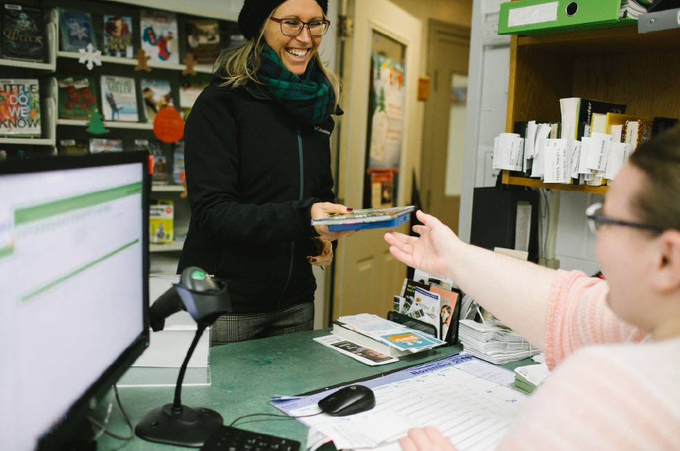 Woman handing her library card to a staff member.