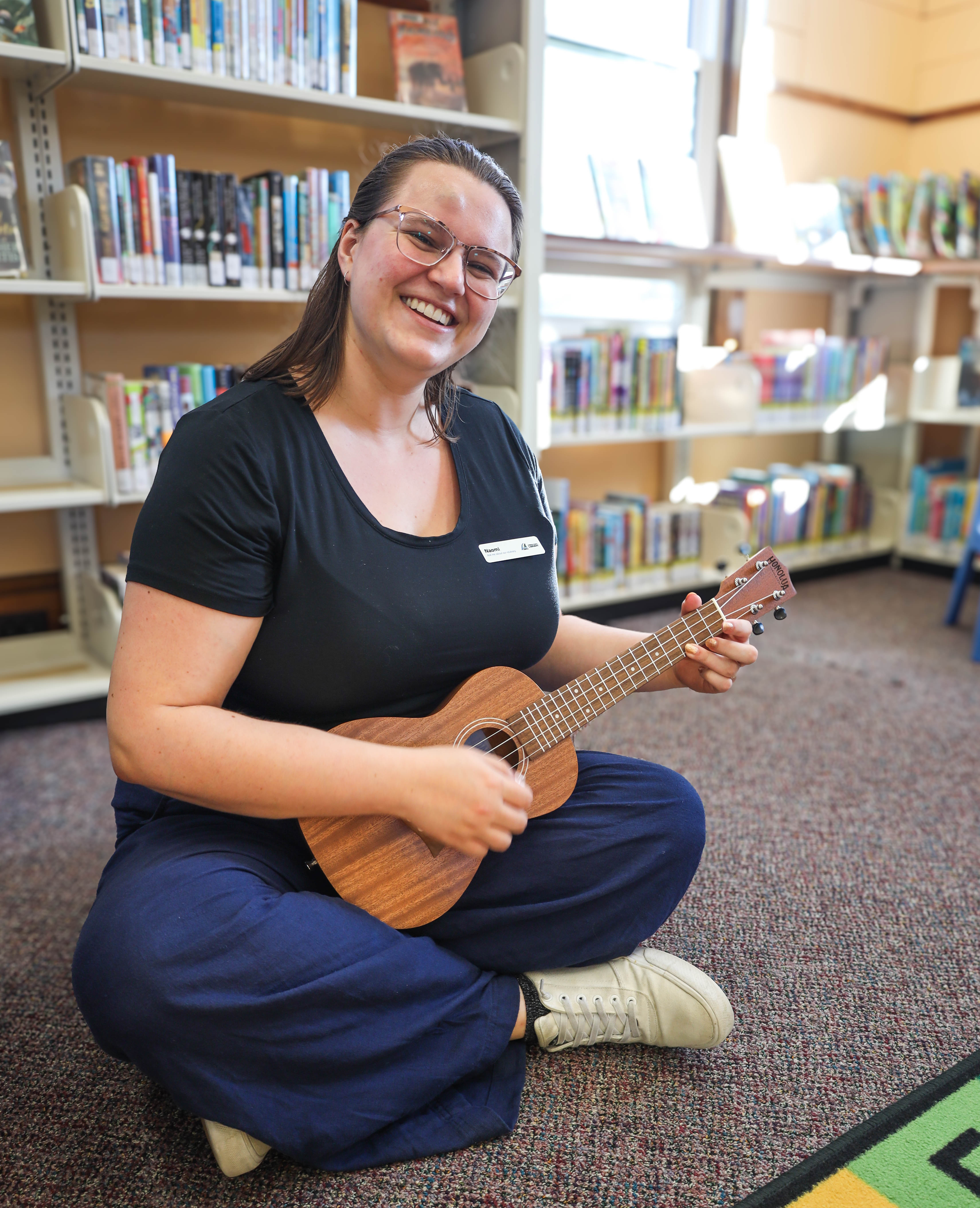 Woman holding a ukelele in a library.