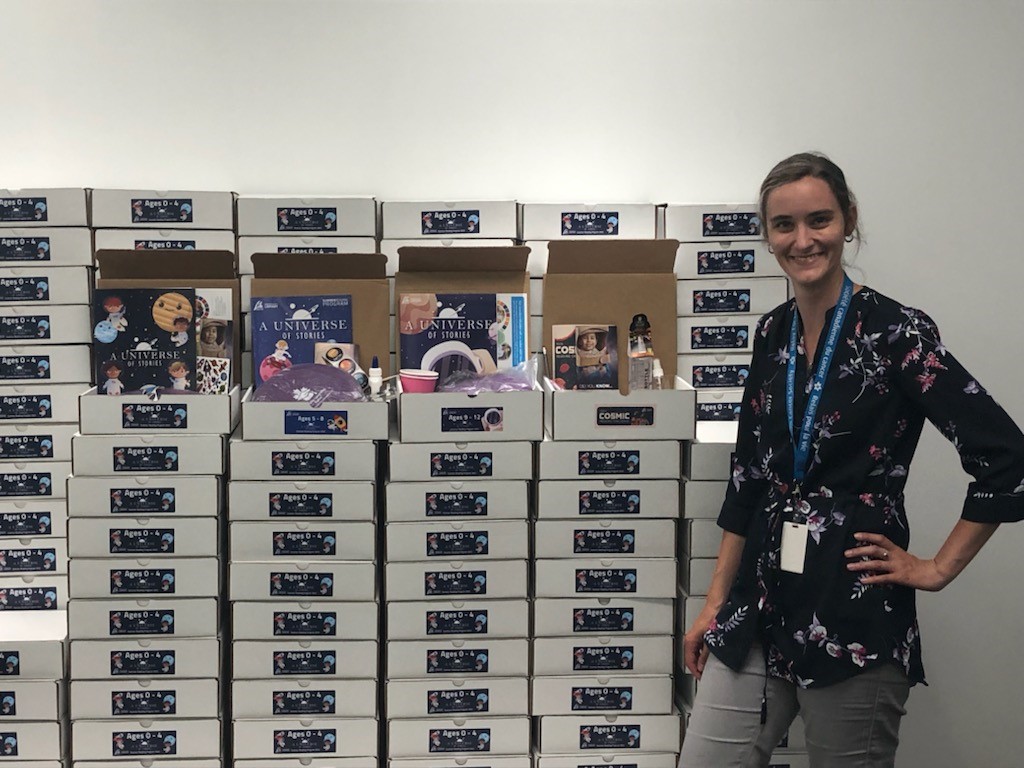 Lady standing next to a stack of white boxes.