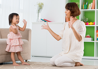 Child and adult woman dancing in a living room