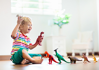 Child playing with toy dinosaurs