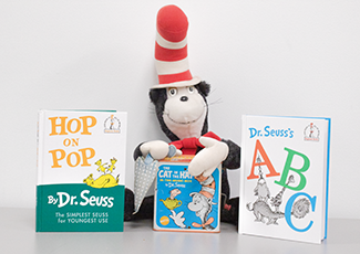 Stuffed cat in the hat toy with two books beside it.