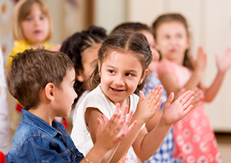 Two children clapping while looking at each other