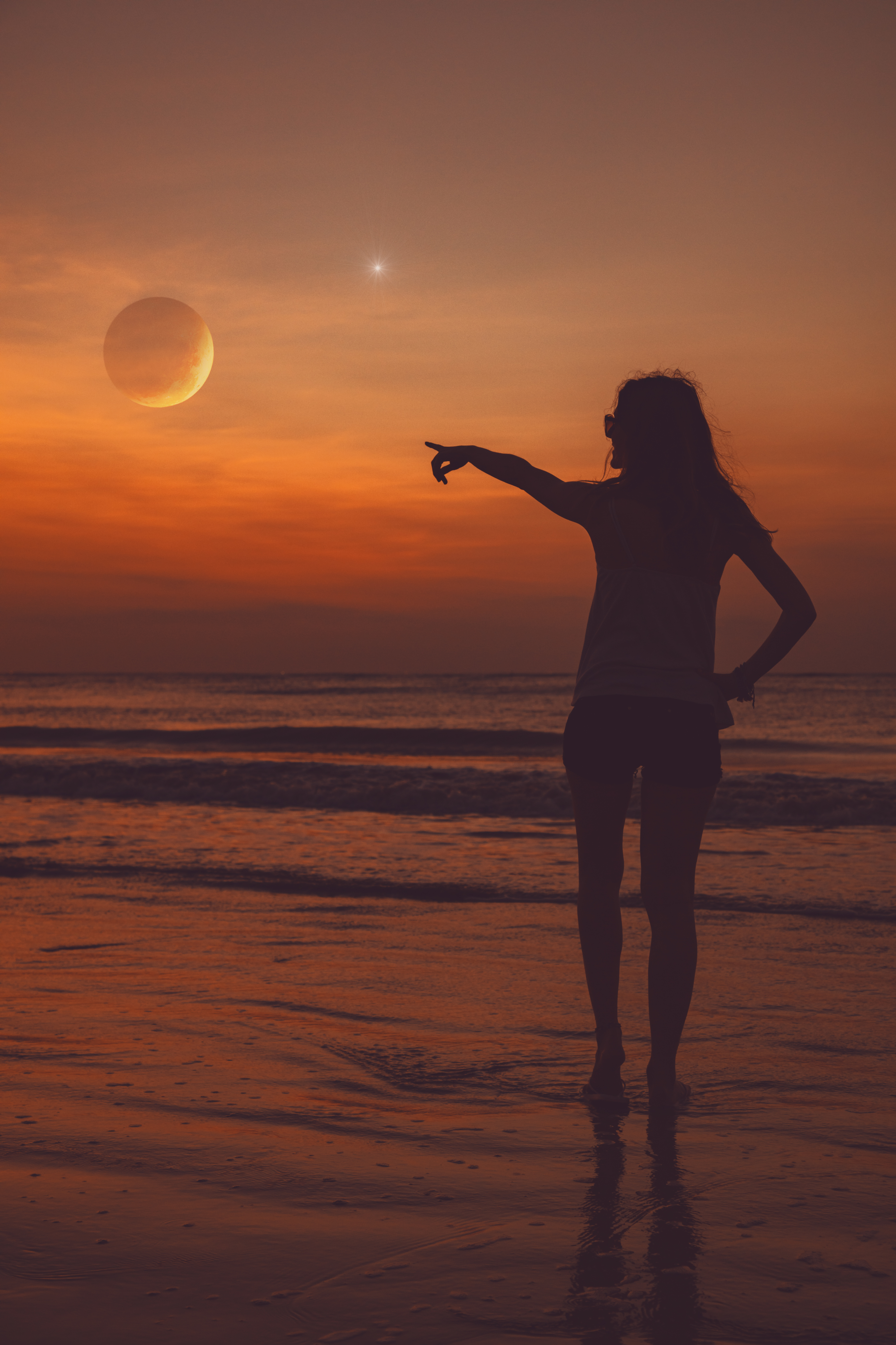 Woman pointing at moon on the beach