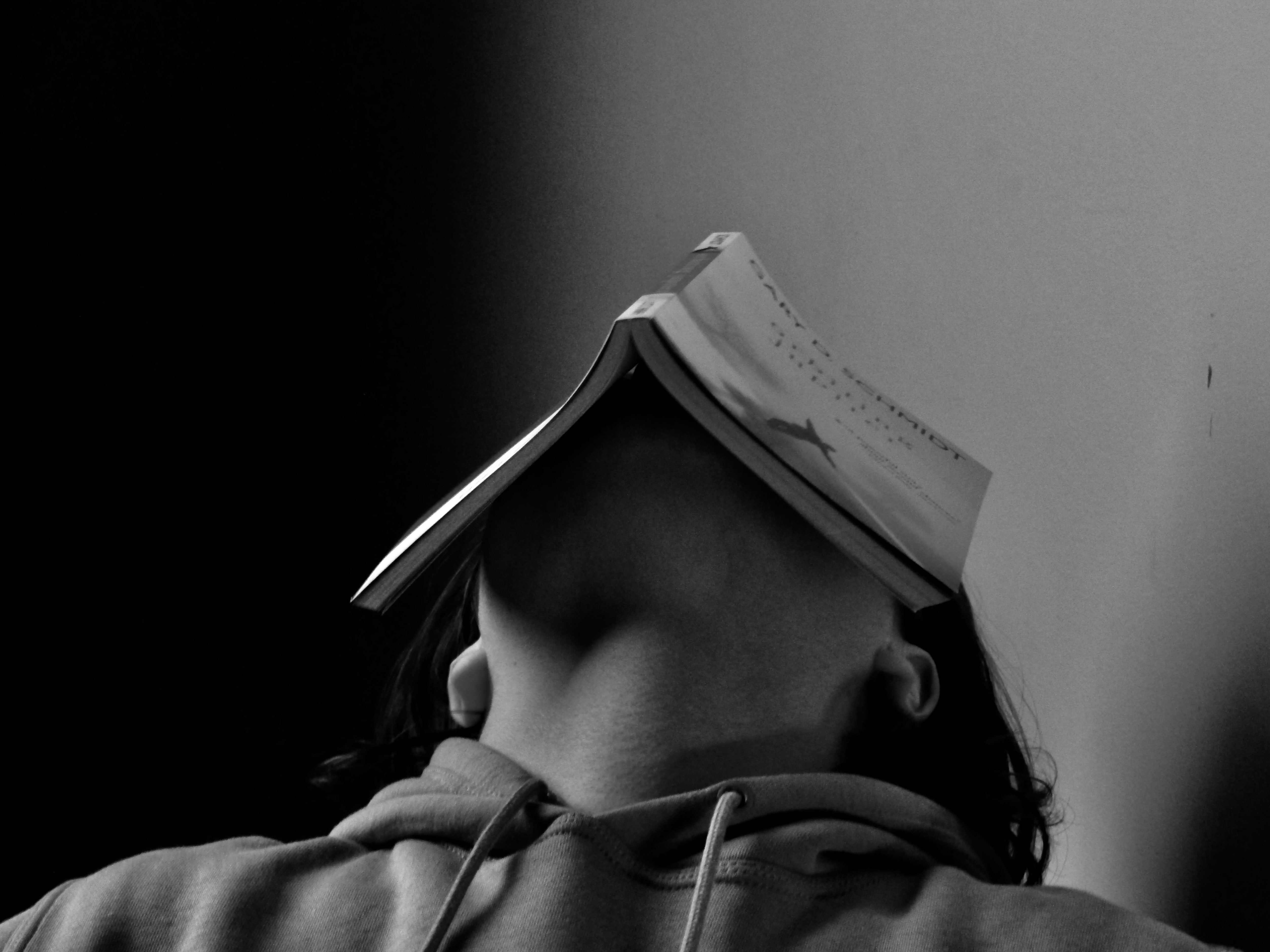 black and white photo of a person with an open book on their head