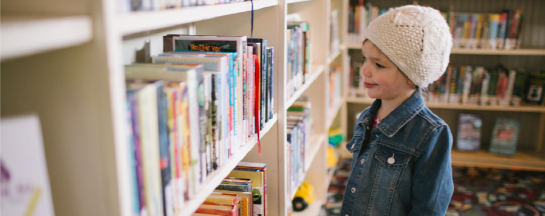 Child holding book at library.