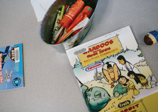 Books, crayons and glue stick on table.