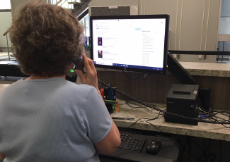 Person on the phone in front of a computer.