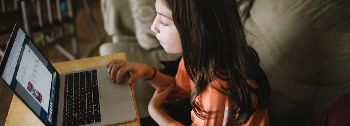 Laptop on a table with a children using it.