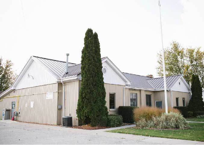 Beige building with grass in front yard with flag pole.