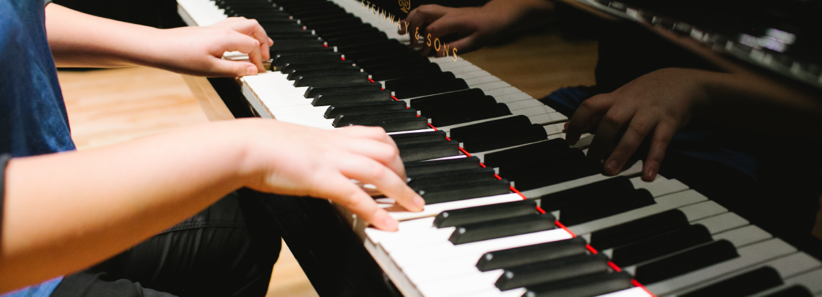 Hands playing the piano keys. 